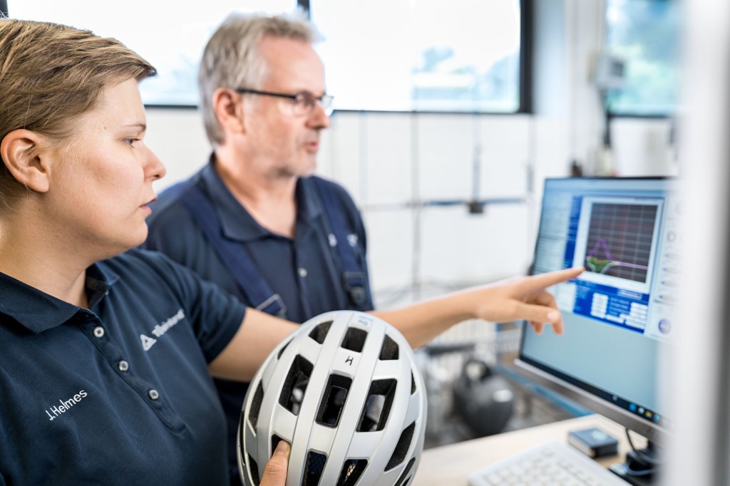 TÜV Rheinland Experten für Helmprüfung vor einem Monitor.