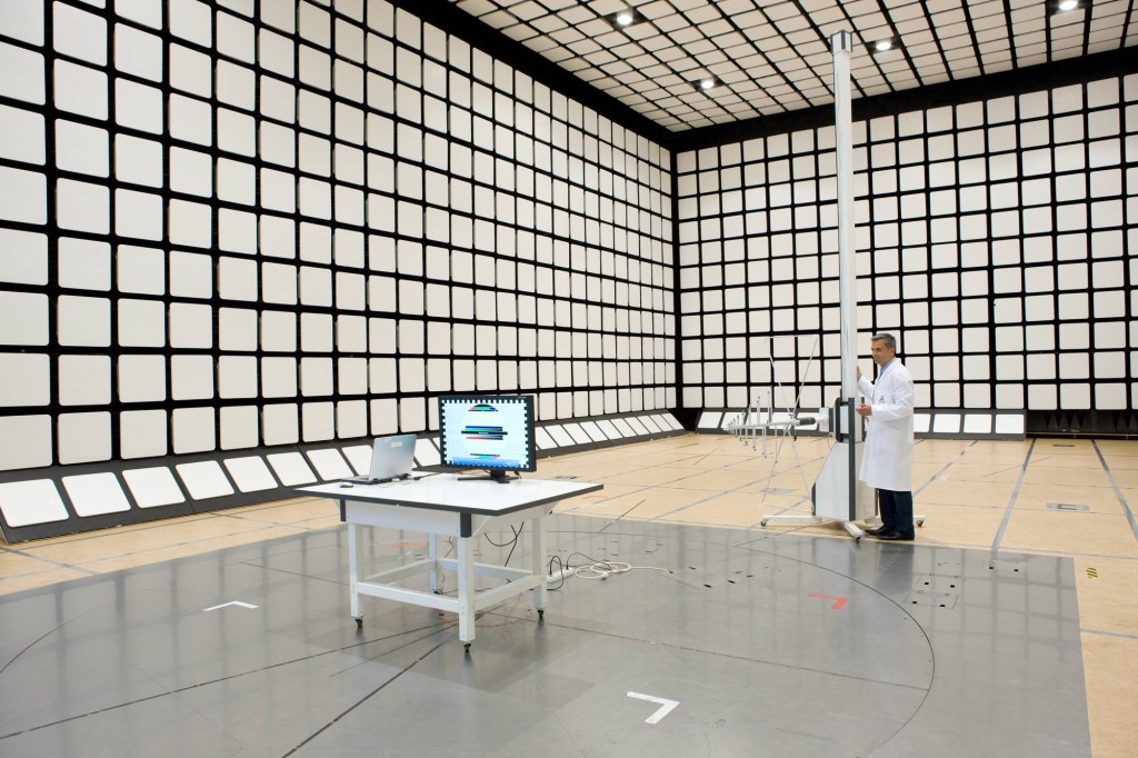 電波暗室のテーブル上に設置されたパソコンと、その前でアンテナを調整しているエンジニア