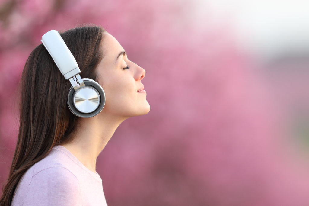 屋外でヘットフォンで音楽を聴いている女性