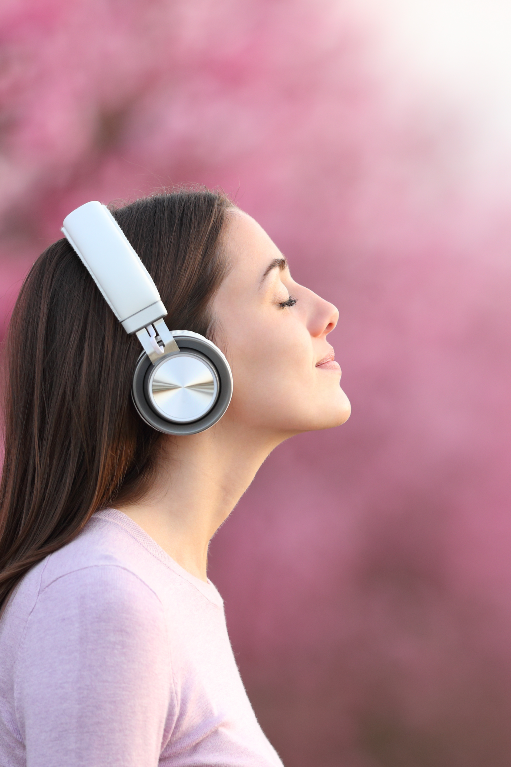 野外でヘットフォンで音楽を聴いている女性