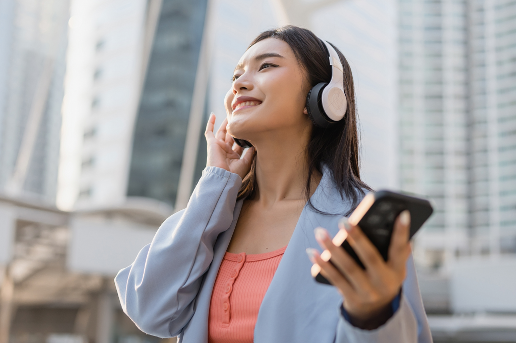 街中でヘッドフォンで音楽を楽しむ女性