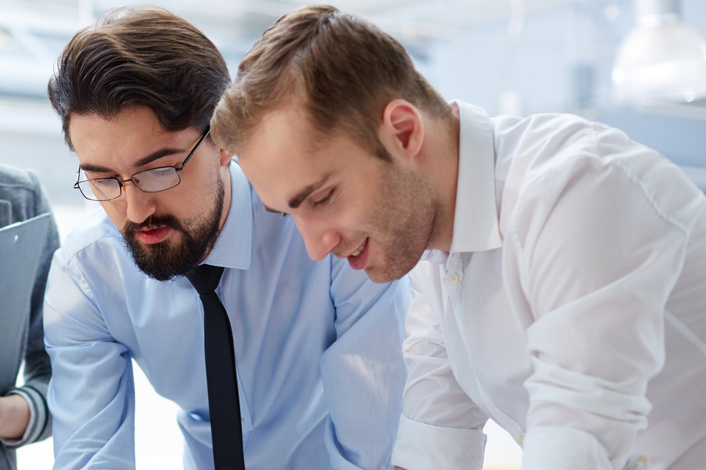 チームメンバーが、テーブルの上に広げられた書類を通じてプロジェクトの詳細を活発に議論し、チームワークとコミュニケーションを促進している。