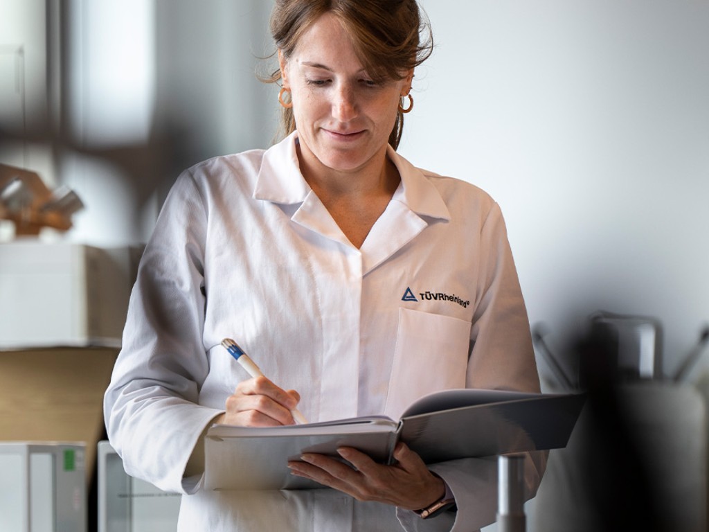 Mitarbeiterin im Labor beim Anfertigen von Notizen | TÜV Rheinland
