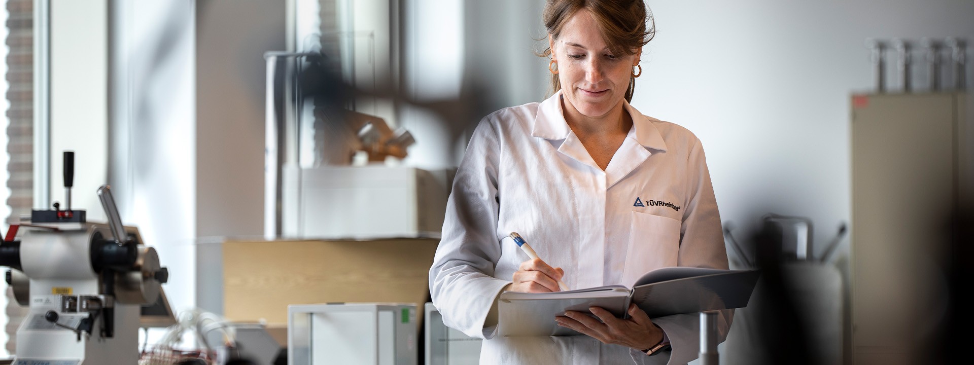 Employee in laboratory taking notes | TÜV Rheinland