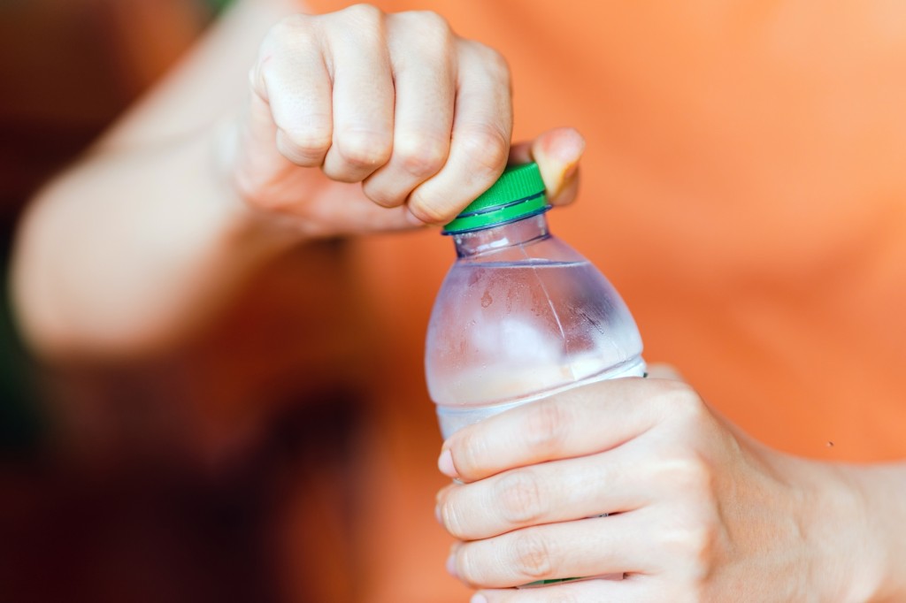 A women's hands unscrewing a small water bottle.