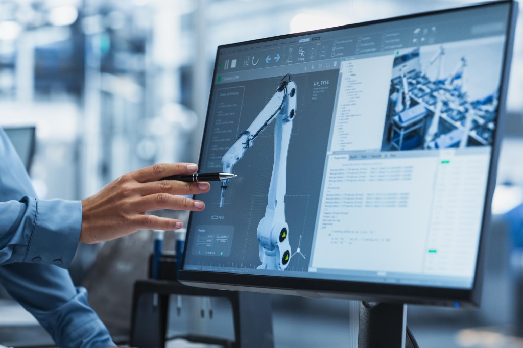 Person is pointing to a screen where we can see the graphic of an industrial robot.