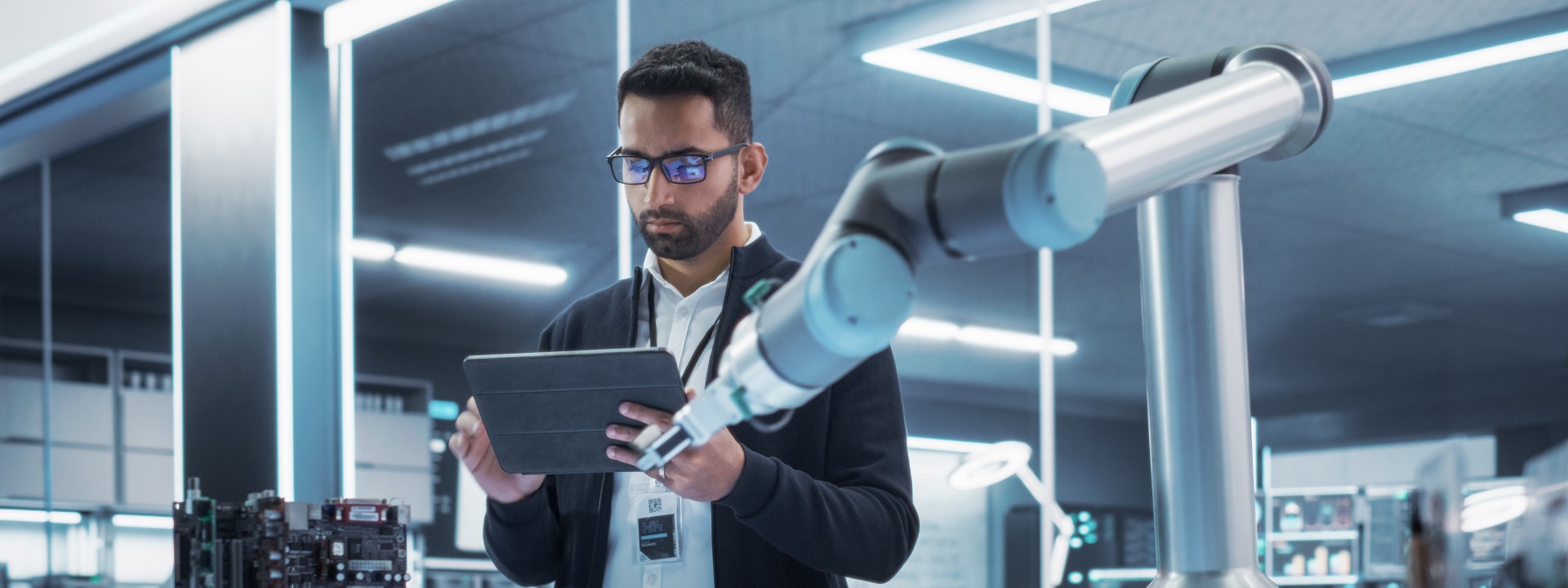 Techniker steuert Roboterarm per Tablet – TÜV Rheinland Prüfservice für Robotik und Automatisierungstechnik.