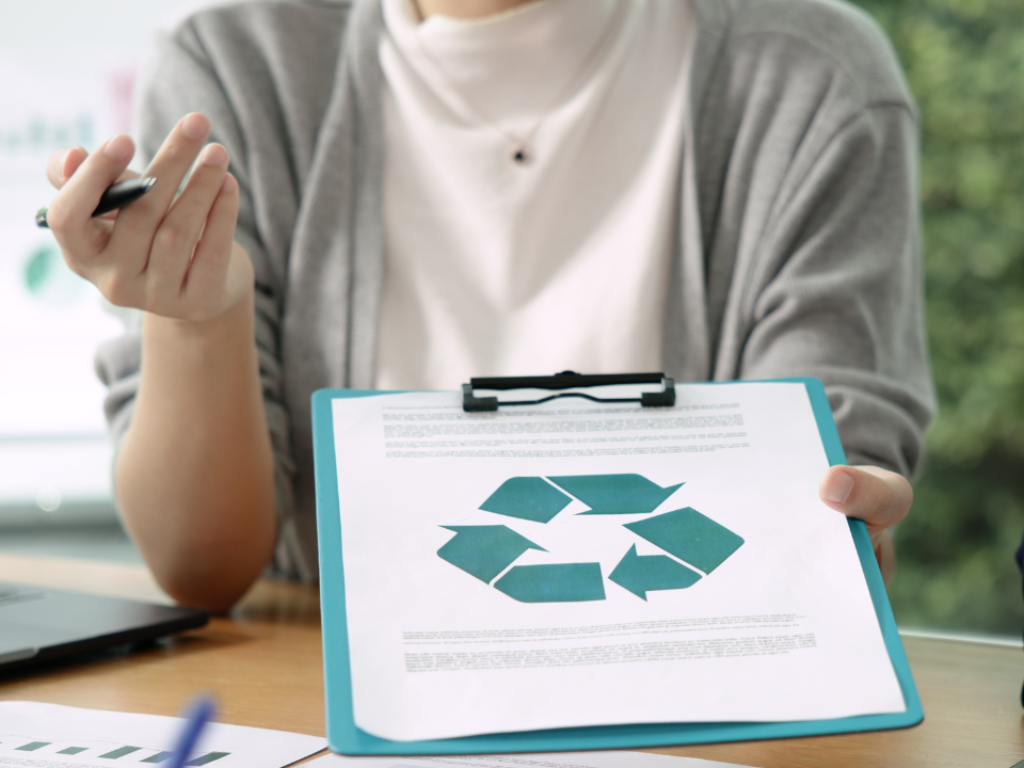 Woman showing a clipboard with a recycling symbol.