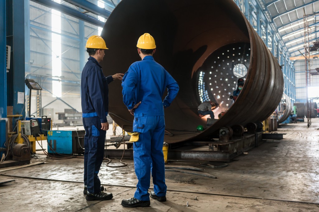 Two industrial workers supervising the manufacture of a heat exchanger