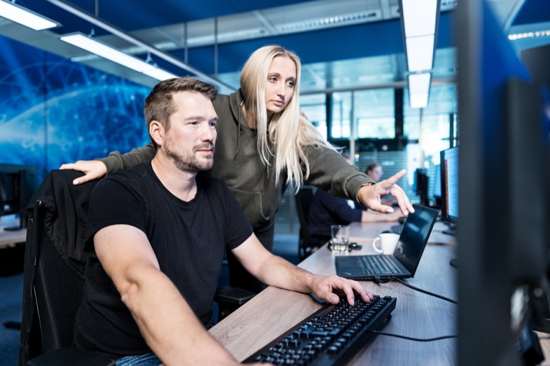 Zwei Kollegen (Mann und Frau) bei der gemeinsamen Betrachtung von Daten auf einem Computerbildschirm im Büro