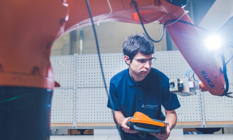 Techniker bedient ein Steuergerät neben einem Industrieroboterarm