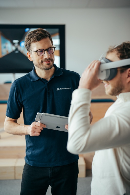 Ingenieur mit Tablet, während ein Kollege ein Virtual-Reality-Headset aufsetzt